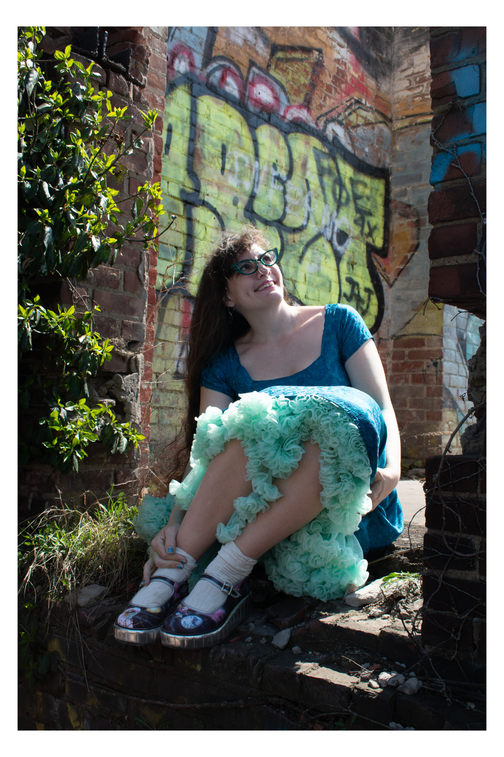 Marie smiles in an urban ruin with graffiti