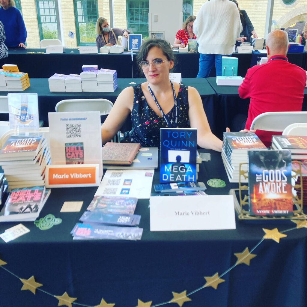 Smiling white lady behind a table full of books.