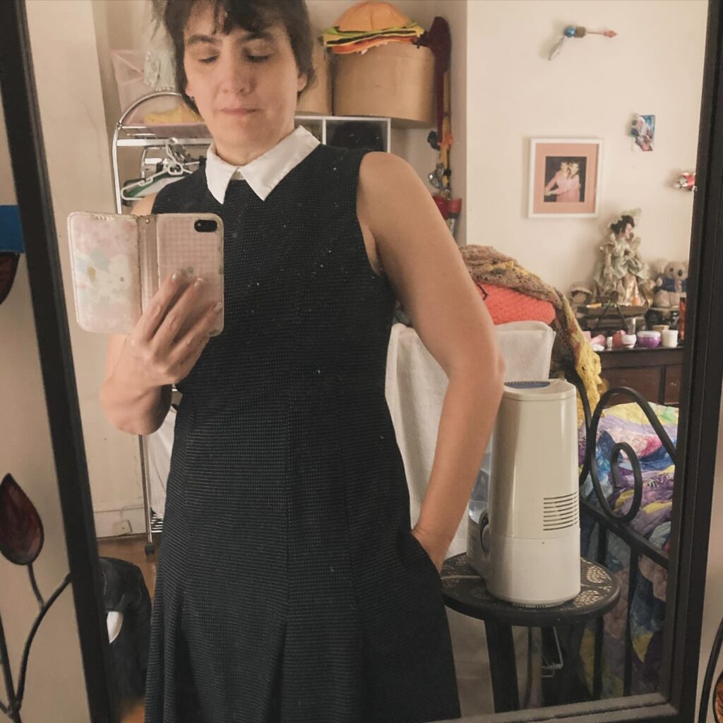 Mirror selfie in black sheath dress with hand in pocket